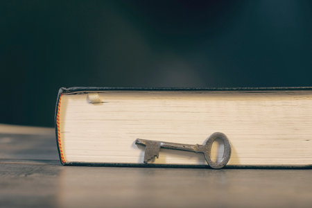 Metal key and book on wooden tableの写真素材