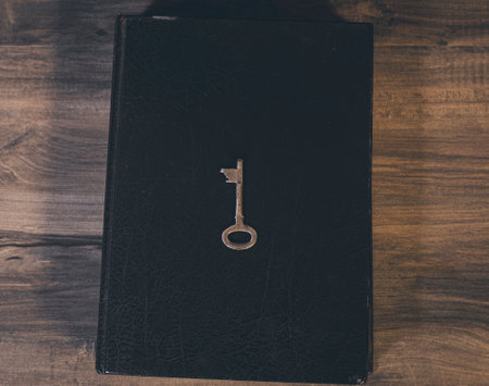 Metal key and book on wooden tableの写真素材