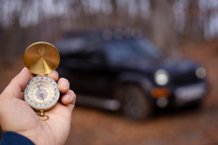 Holding a compass in front of a car during the day