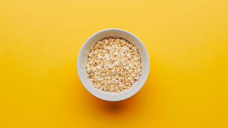 bowl of oatmeal on a yellow background. oatmeal porridge. top viewの素材