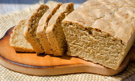 Oatmeal bread on a wooden board. Cut into small pieces.