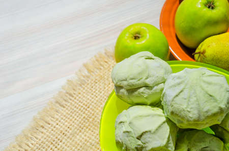 Green marshmallows on a plate against the background of pears and apples.の写真素材
