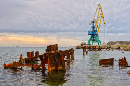 A construction crane works on the Black Sea coast in Crimea. Remains of a rotten pier.