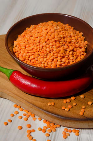 Lentils in a bowl and with red pepper on the board. A genus of herbaceous plants in the legume family.の写真素材