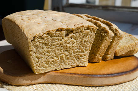 Handmade bread on a wooden board, on a wheat and oatmeal. cut into pieces.の写真素材