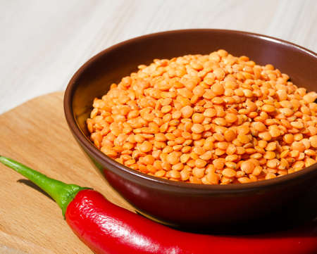 Lentils in a bowl and with red pepper on the board. A genus of herbaceous plants in the legume family.の写真素材