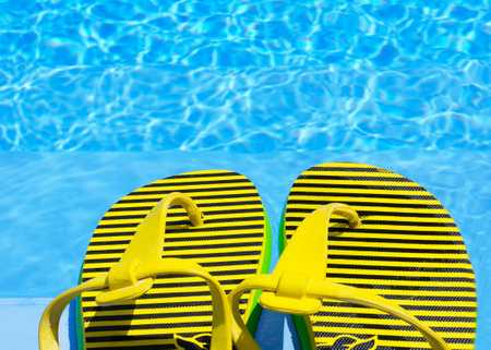 Flip flops in the pool. Bright and colored slippers on the background of the pool. Colors of the flag of Ukraine.の写真素材
