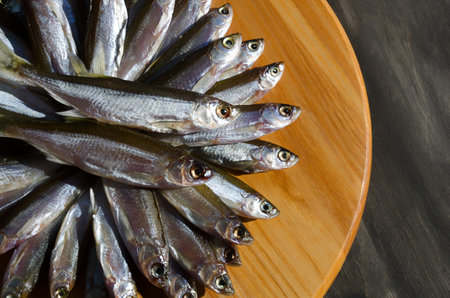 Dried fish black on a wooden board. Very tasty, fatty fish for beer.の写真素材