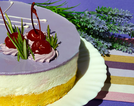 Mousse dessert decorated with cherries and rosemary sprigs on a white plate on a purple background. Delicious birthday cake.の写真素材