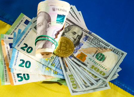 Bitcoin, Dollars, Euro and Hryvnia on the background of the Ukrainian flag. Assistance to the Ukrainian people from the European Union and the United States in connection with the invasion of Russian troops.の写真素材