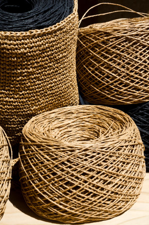 Raffia balls close-up on a wooden board. Skeins of black and beige raffia are ready for knitting.の写真素材
