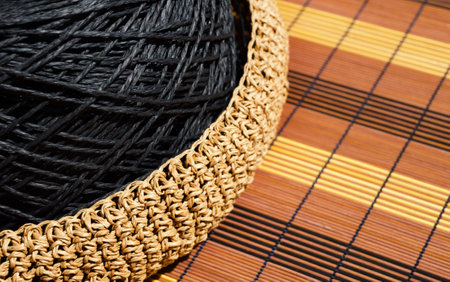 A skein of black raffia in a woven bowl of beige raffia. handmade, hobby.の写真素材