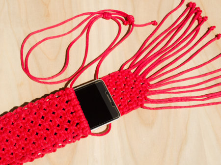 Red small bag knitted using macrame technique for a mobile phone. Hobby, needlework.の写真素材