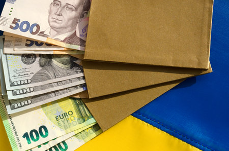 Money in an envelope on the Ukrainian flag. Hryvnia currency, dollars and euros. Assistance to Ukraine from countries in connection with the military aggression of Russia.の写真素材