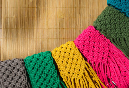 Small handbags knitted with macrame technique on a bamboo background. Multi-colored bags for mobile phones.の写真素材