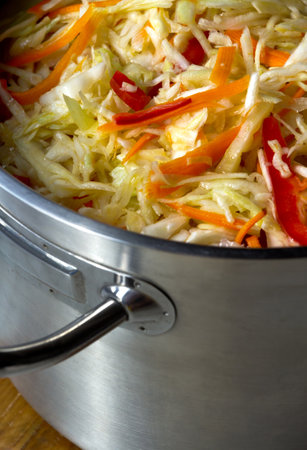 Chopped vegetables in a large saucepan. Sauerkraut with carrots and peppers in a large saucepan.の写真素材