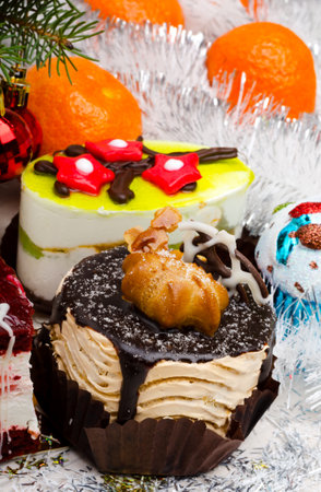 New Year's cakes, Christmas tree branches, balls, tangerines, tinsel and bow. Place for text. Festive mood of Christmas and New Year.の写真素材