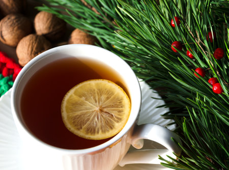 A cup of morning tea with lemon and walnuts against a background of green branches of a Christmas tree. Decorations for the New Year and Christmas. A place for congratulations.の写真素材
