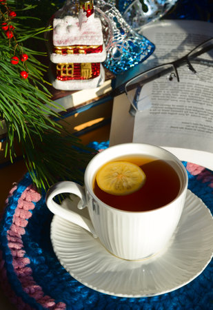 A cup of morning tea with lemon against the background of green Christmas tree branches. Decorations for the New Year and Christmas. A place for congratulations.の写真素材