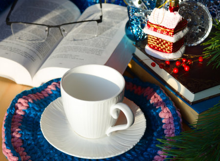 An empty cup for tea or coffee against a background of books and green Christmas tree branches. Decorations for the New Year and Christmas. A place for congratulations.の写真素材