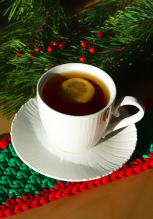 A cup of morning tea with lemon against the background of green Christmas tree branches. Decorations for the New Year and Christmas. A place for congratulations.の写真素材