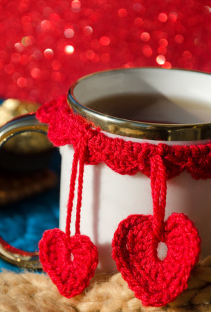 Cup of tea with hearts. Beautiful mug for Valentine's Day on a red background with lights.の写真素材
