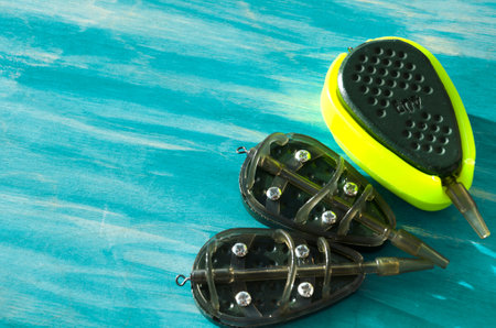 Flat feeders for fishing, accessories for fishing, top view on a turquoise background.
