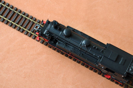 Toy locomotive and railroad with selective focus effect, top view. Model of a locomotive on a dark background.の写真素材
