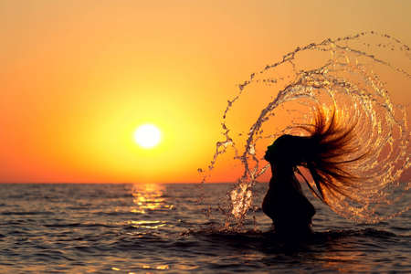 silhouette of a beautiful girl diving into the seaの写真素材