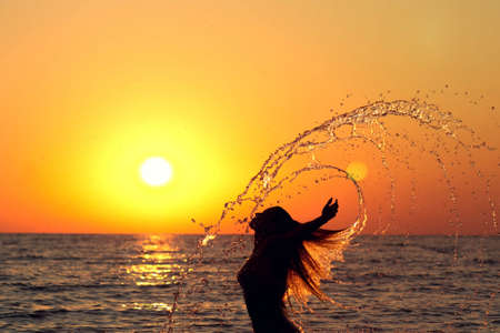 silhouette of a beautiful girl diving into the seaの写真素材