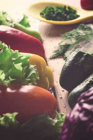 Sweet red and yellow peppers, cucumber, lettuce on a kitchen boardの写真素材