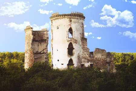 The ruins of an ancient palace of cylindrical shape on a picturesque hill covered with trees against...