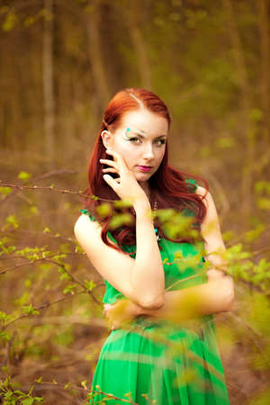 Beautiful red-hair lady in green dress with fairy make-upの写真素材