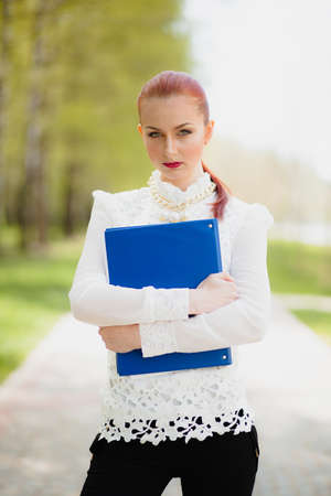 Beautiful girl with blue office folder outdoorの写真素材