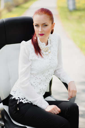 Beautiful girl sitting on the leather office chair outdoorの写真素材