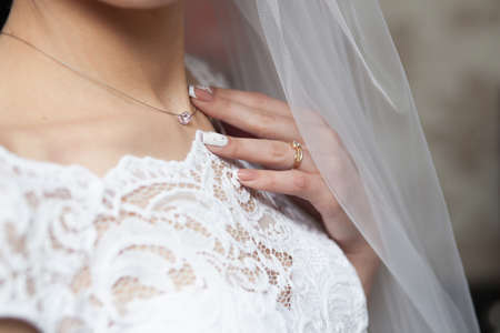 Bride's neck with necklace holding in handの写真素材