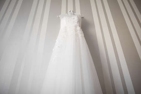Beautiful wedding dress hanging on the wallの写真素材