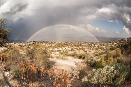Mountain rocky landscape with rainbow and cloudsの写真素材