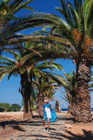 Pretty girl in red sunglasses posing on the stony road among the palm treesの写真素材
