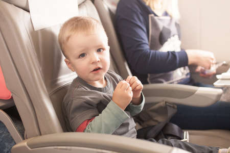 Boy sitting in the airplane chair looking straight at the camera