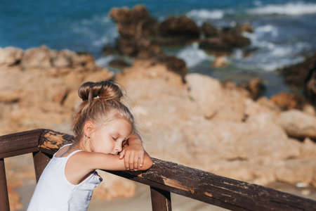 Beautiful girl posing on the seashore with eyes shutの写真素材
