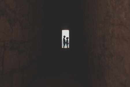 Boy and girl silhouettes with wate in the backgroundの写真素材