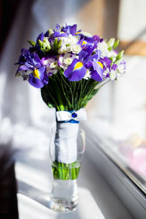 A Bucket of purple flowers standing near the windowの写真素材