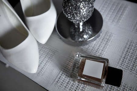 Wedding bride's elements such as shoes and perfume on the table on the striped background