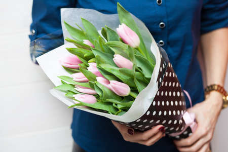 A girl hoding beautiful spring tulips in her handsの写真素材