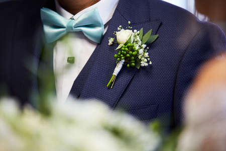 Groom's chest in suit with a boutonniere and a bowtieの写真素材