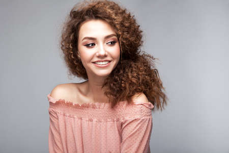 Very beautiful girl model with afro curls and soft smiling face in sudio on neutral grey backgroundの写真素材