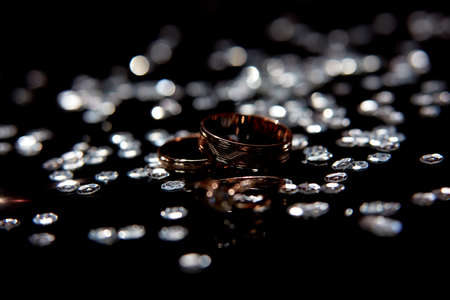 Golden wedding rings for bride and groom amond splashes of waterの写真素材
