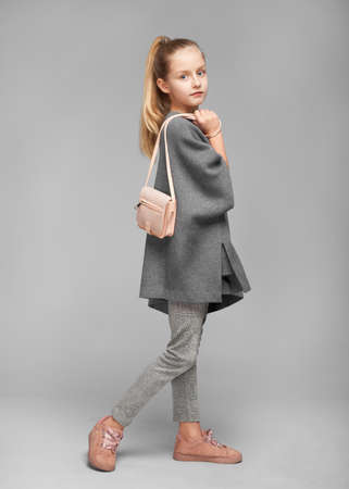 Cute stylish girl in grey dress and with a nandbag in the photostudio on grey backgroundの写真素材