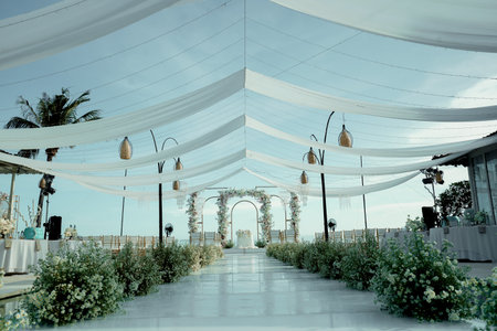 Minimalist outdoor wedding altar decoration with hanging lights and flowers under a beautiful blue sky (1)の写真素材